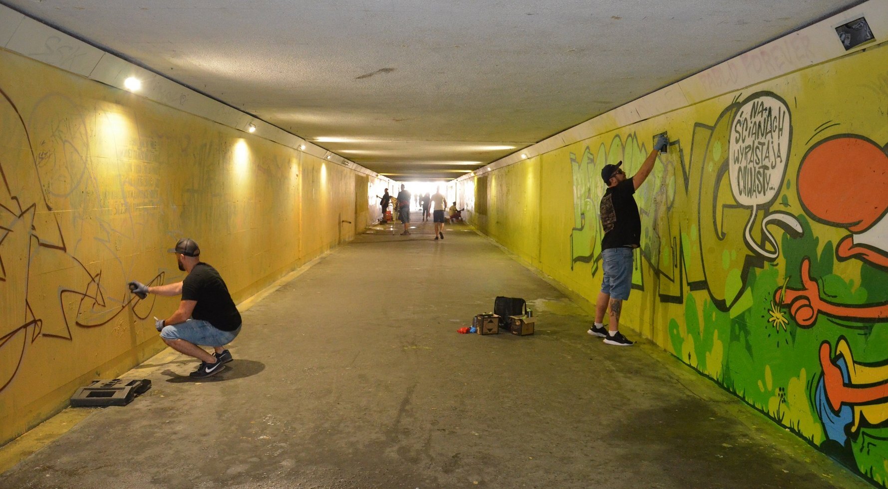 Artysci maluja mural w przejsciu pod torami laczacym ulice Wojewodzka i 3